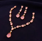 Jewelry set with pink teardrop-shaped stones and gold accents on a dark background