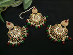 Ornate gold jewelry set with red and green stones on a dark background