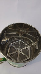 Metal tea infuser with green handle on a white background