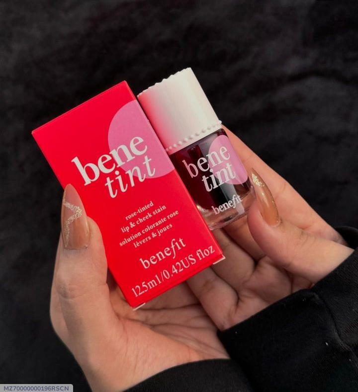 Benefit benetint lip and cheek tint with red packaging held in a hand against a dark background