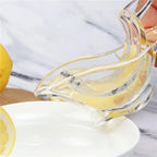Clear glass lemon squeezer with lemons on a marble surface