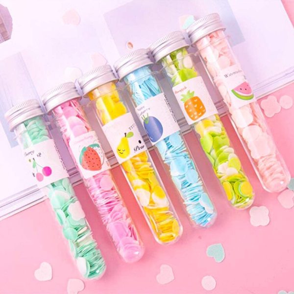 Set of colorful gelatin dessert in transparent tubes with fruit-themed labels on a pink background.