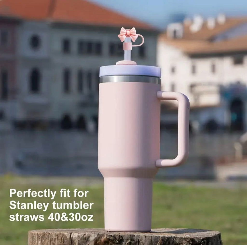 Pink tumbler with straw attachment on a wooden stump in an outdoor setting