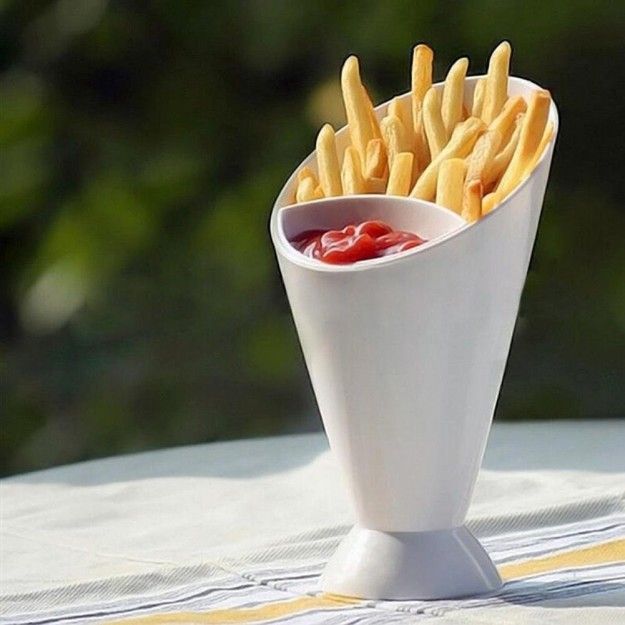 White cone-shaped holder with french fries and ketchup on a blurred green background