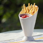 White cone-shaped holder with french fries and ketchup on a blurred green background