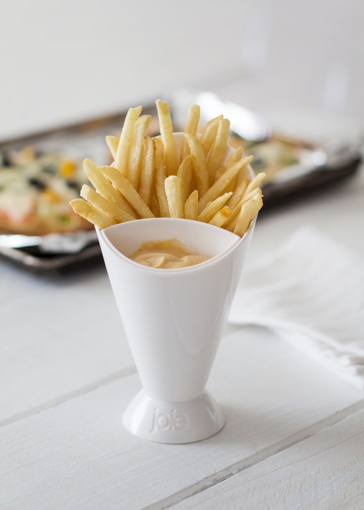 White ceramic cup filled with French fries on a light wooden surface