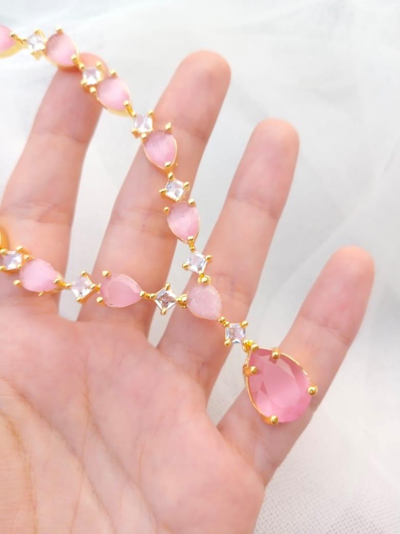 Hand wearing a pink gemstone bracelet with gold accents on a white background