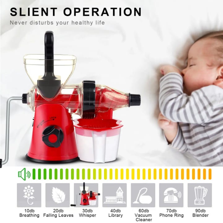Red manual juicer with a baby sleeping in the background, emphasizing quiet operation.