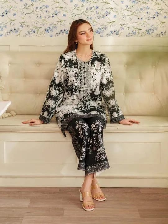 Woman sitting on a couch wearing a black and white floral outfit with intricate patterns.