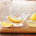 Glass lemon squeezer with lemons on a wooden cutting board