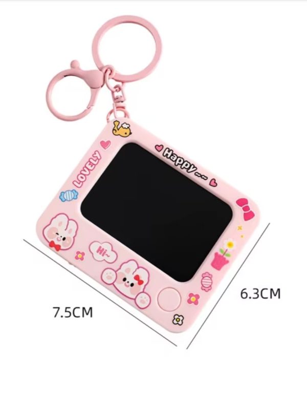 Pink cartoon-themed keychain with a small screen and measurements on a white background