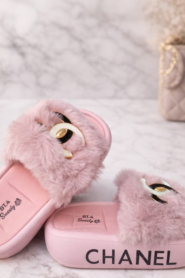 Pink Chanel slippers with fluffy texture on a soft surface