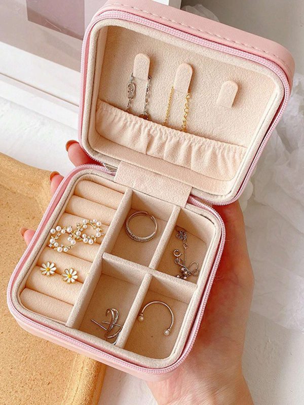Pink jewelry box with compartments holding various earrings and a ring.
