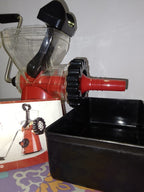 Manual juicer with a black container on a colorful surface