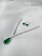 Jewelry set with green teardrop pendant necklace and earrings on a white fabric background
