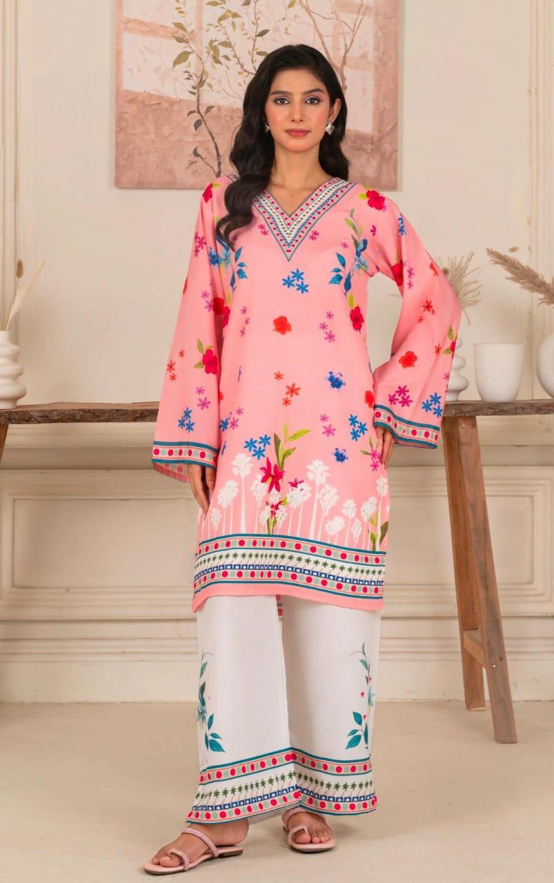 Woman wearing a pink embroidered kurta with white pants in a decorated room.