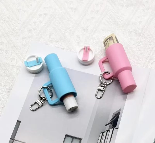 Two lip balm keychains, one blue and one pink, on a textured white surface.