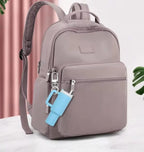 Gray backpack with a blue keychain on a light background