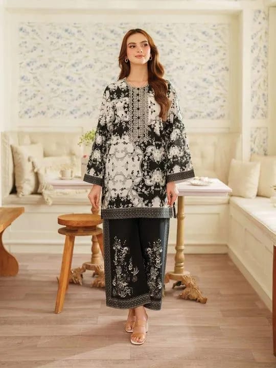 Woman in a black and white floral outfit standing in a decorated room.