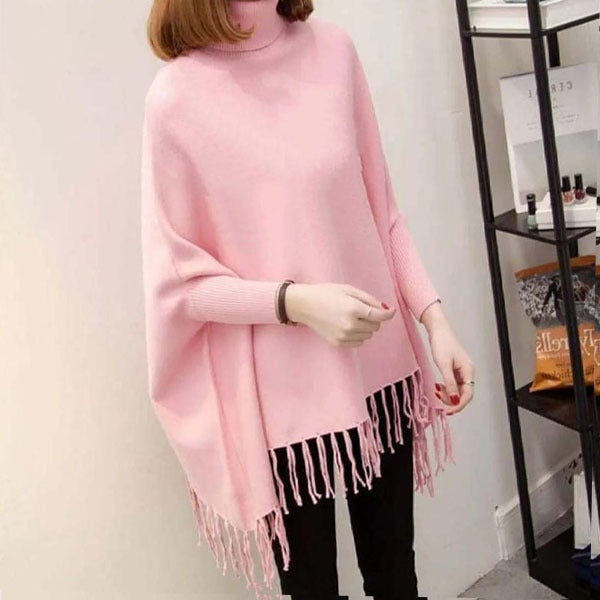 Person wearing a pink poncho with tassels indoors.