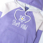Purple hoodie with 'Stay Wild' text and flower graphic on a white background