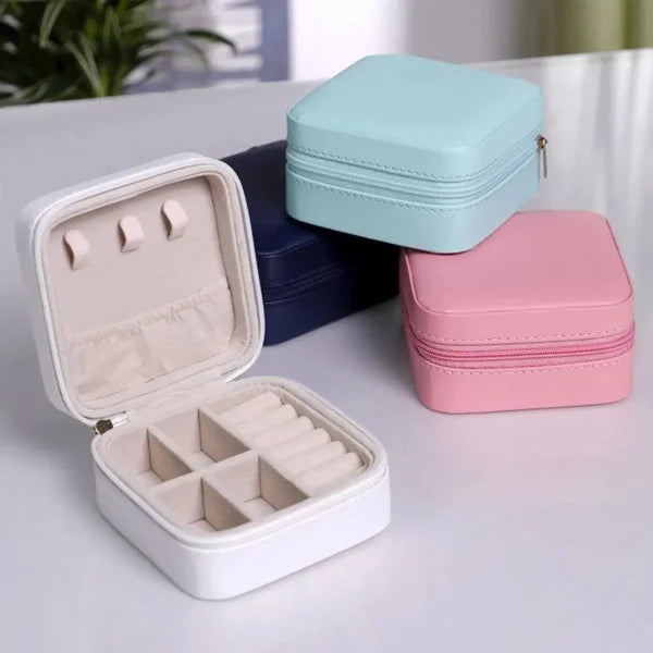 Jewelry cases in white, blue, and pink on a light surface.