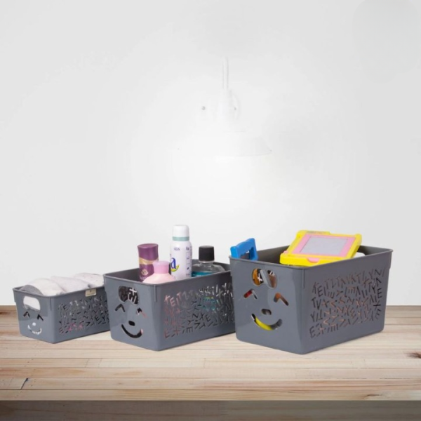 Three gray storage bins with smiley face designs on a wooden surface.